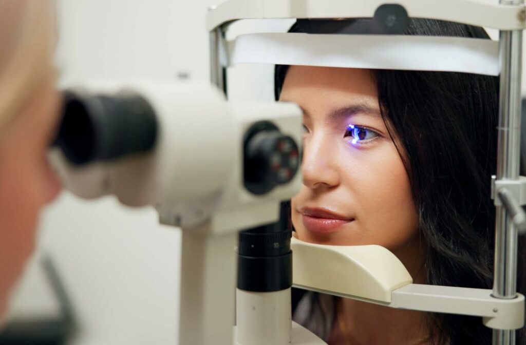 Patient undergoing eye exam with diagnostic laser device pointed at her eye.