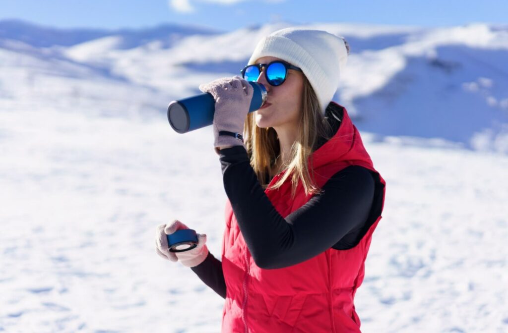 Woman wearing polarized sunglasses in snowy outdoor setting, reducing glare from sunlight reflecting off the snow.