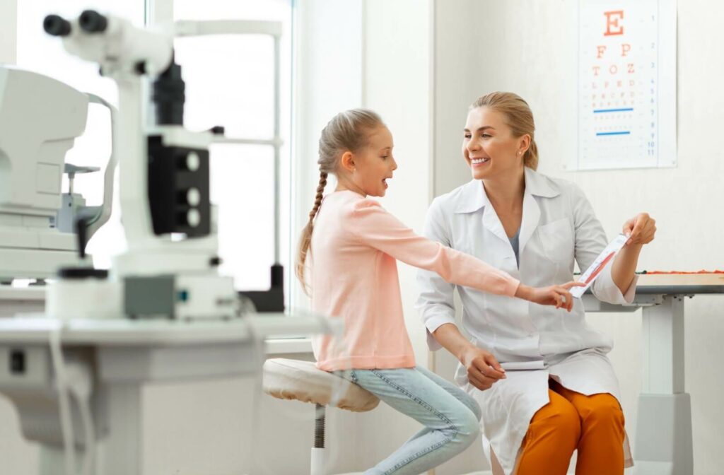 An eye doctor uses a diagram to explain to a young patient why myopia progresses during their routine eye exam.