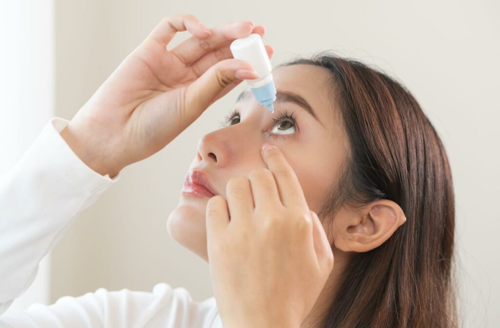 Person putting eye drops into their left eye.