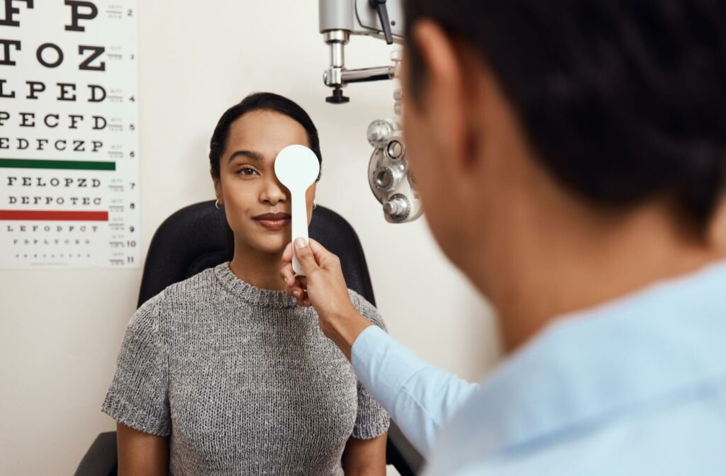 Patient undergoing a comprehensive eye exam with an optometrist using an occluder during vision testing.